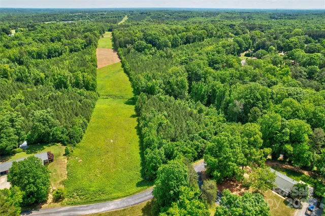 an aerial view of residential houses with outdoor space and trees all around