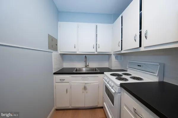 a kitchen with granite countertop a sink a stove and cabinets