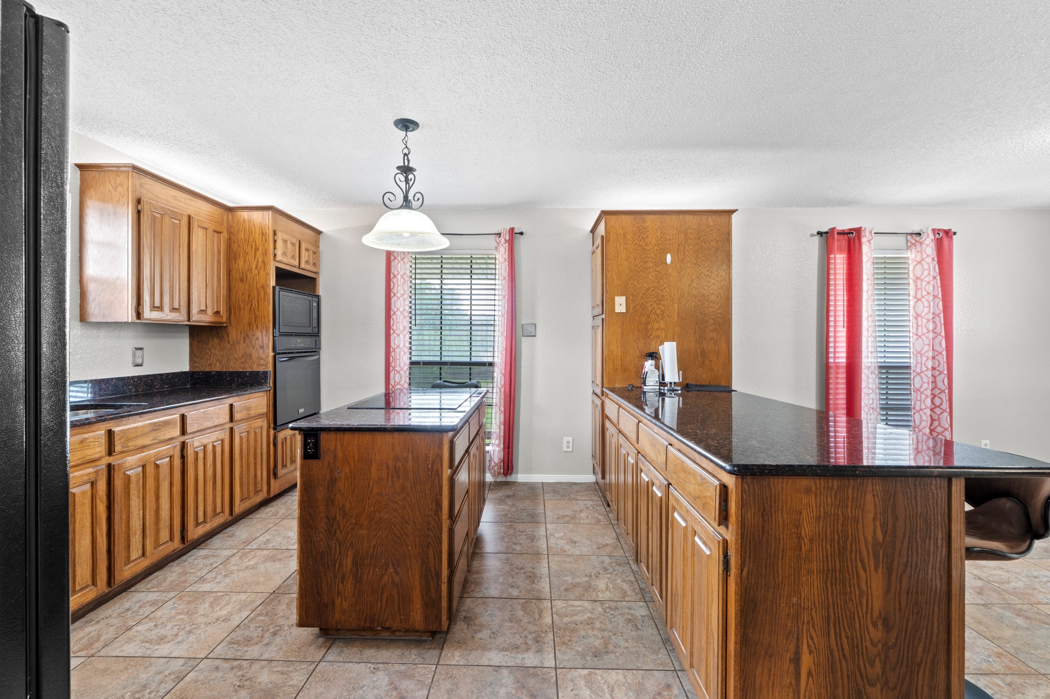 205 Sedro Trail Georgetown, TX 78633 - Photo 13 of 32 A well-equipped kitchen features a central island, ample wood cabinetry, and sleek dark countertops.