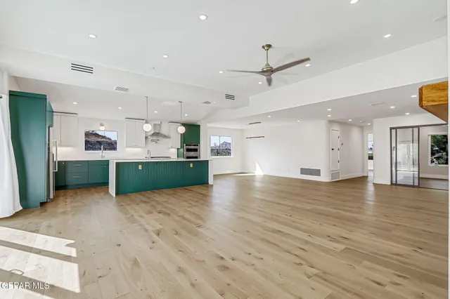 an empty room with wooden floor kitchen view and a window