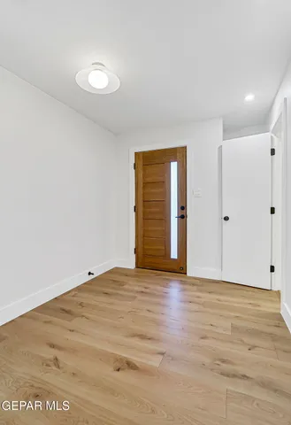 a view of an empty room with wooden floor and a ceiling fan