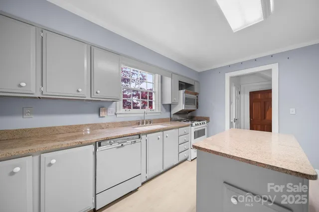 a kitchen with stainless steel appliances granite countertop a sink and cabinets with wooden floor