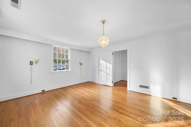 a view of an empty room with window and wooden floor