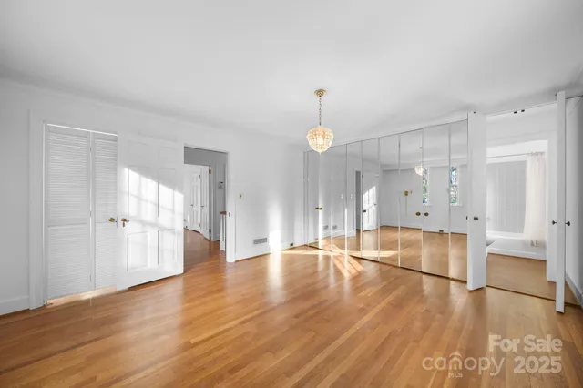 a view of an empty room with wooden floor and windows