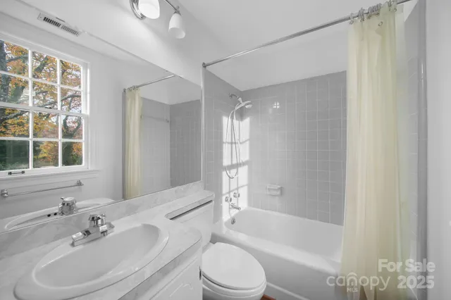 a bathroom with a bathtub shower sink vanity mirror and toilet