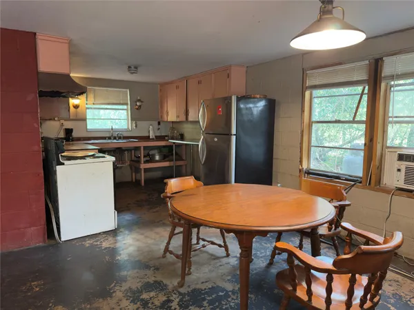 a kitchen with stainless steel appliances granite countertop dining table chairs refrigerator and sink