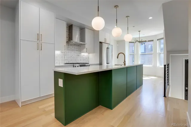 a kitchen with kitchen island stainless steel appliances a sink cabinets and wooden floor