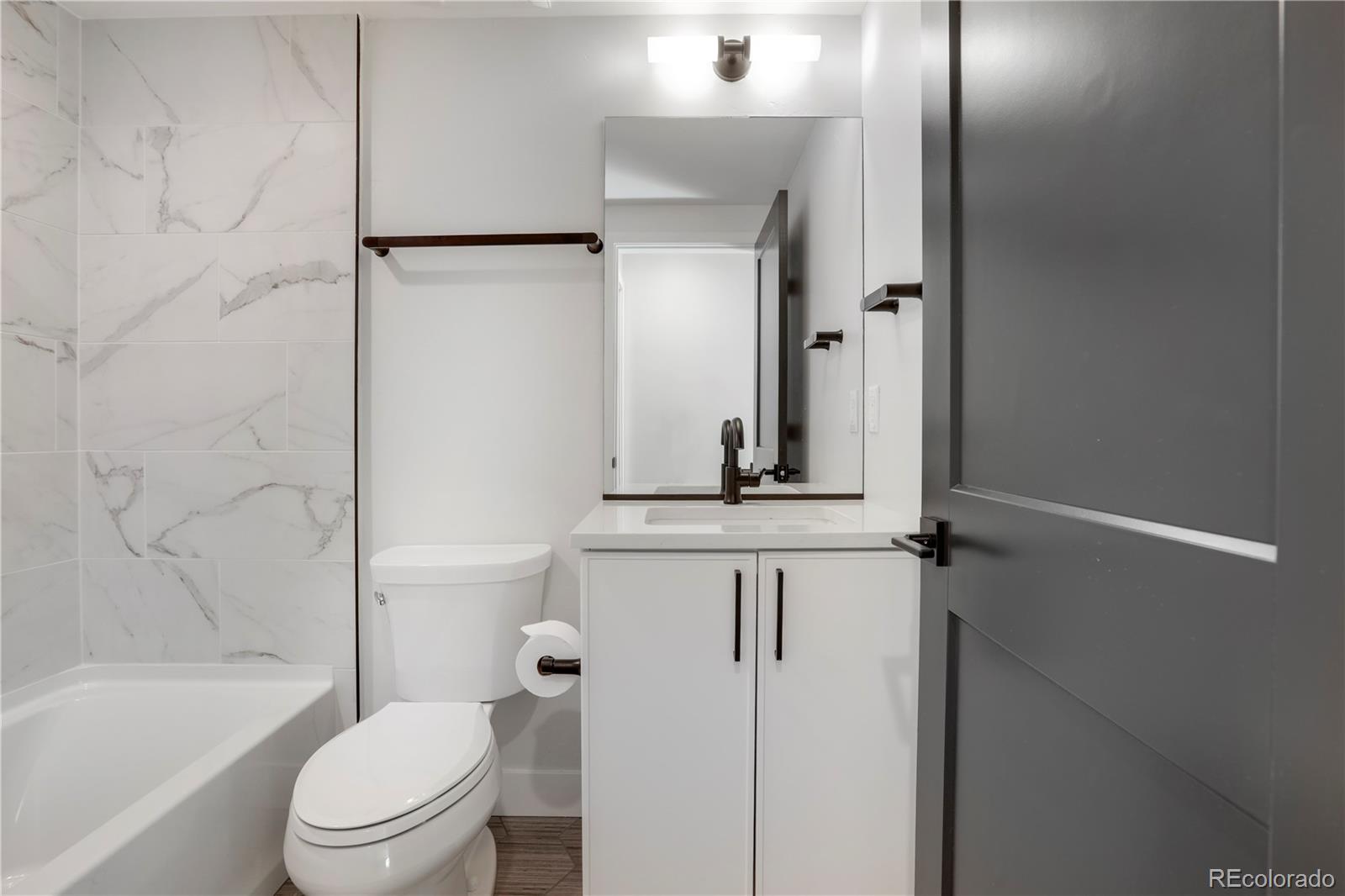 1065-25 25th Street, Unit A Denver, CO 80205 - Photo 22 of 45 a bathroom with a granite countertop sink toilet a mirror and shower