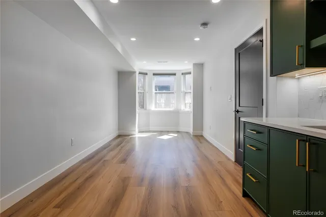 an empty room with wooden floor cabinet and windows