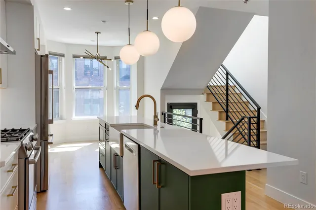 a kitchen with a sink a kitchen island a stove and a wooden floor