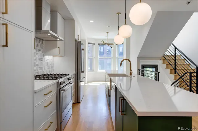 a kitchen with stainless steel appliances granite countertop a stove a sink dishwasher and white cabinets with wooden floor