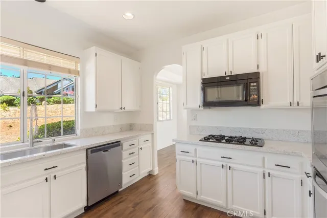a kitchen with stainless steel appliances white cabinets a stove a sink and a window