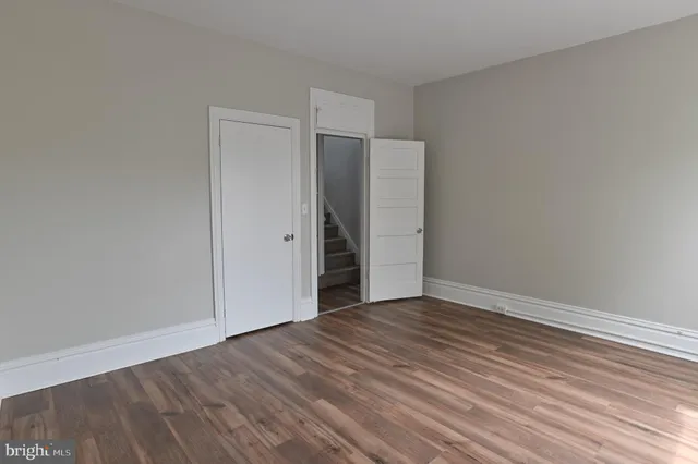 a view of an empty room with wooden floor and closet