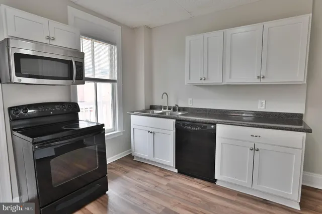 a kitchen with white cabinets and appliances