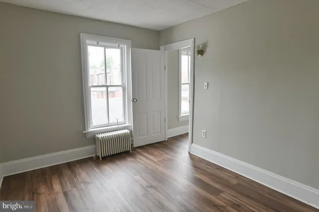 an empty room with wooden floor and window