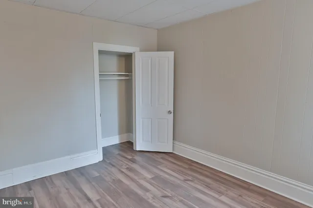 a view of an empty room with wooden floor and closet