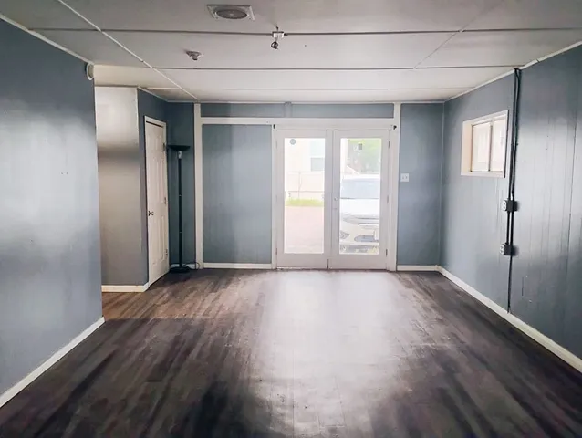 a view of an empty room with wooden floor and window
