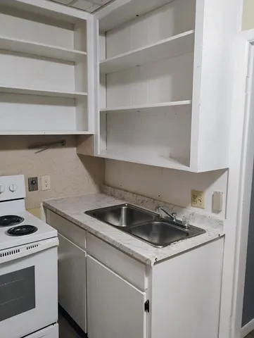 a kitchen that has a sink and a stove with white countertops