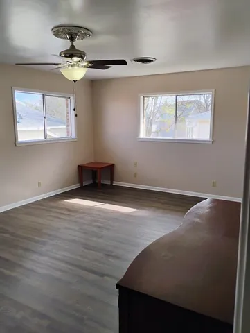 a view of an empty room with wooden floor and a window