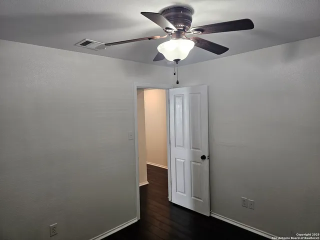 an empty room with wooden floor and fan
