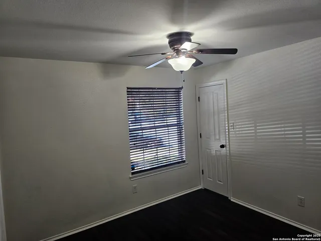 an empty room with a window and a fan