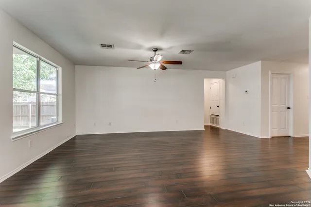 a view of an empty room with a window and a ceiling fan