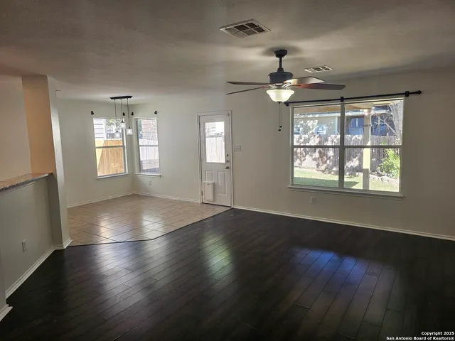 an empty room with wooden floor chandelier and windows