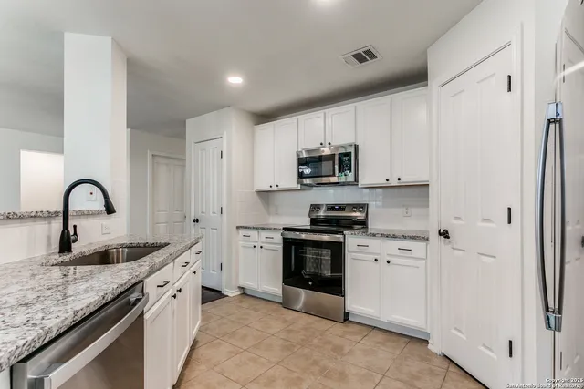 a kitchen with stainless steel appliances granite countertop a sink a stove and a refrigerator with wooden cabinets