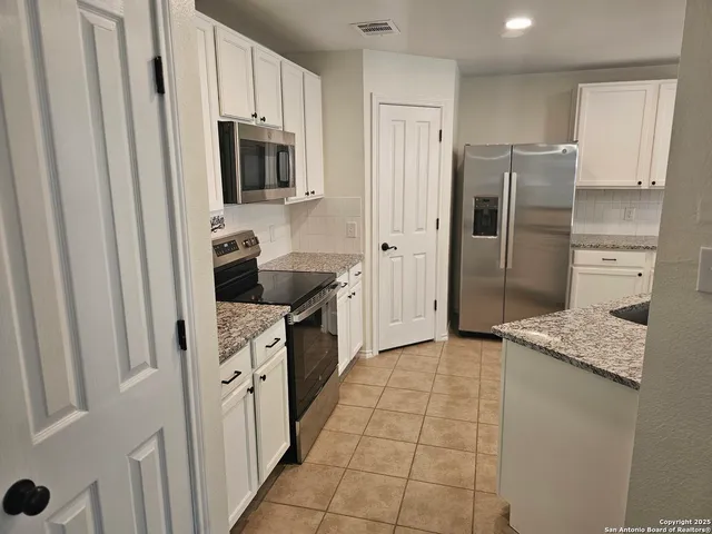 a kitchen with stainless steel appliances granite countertop a refrigerator and a stove top oven