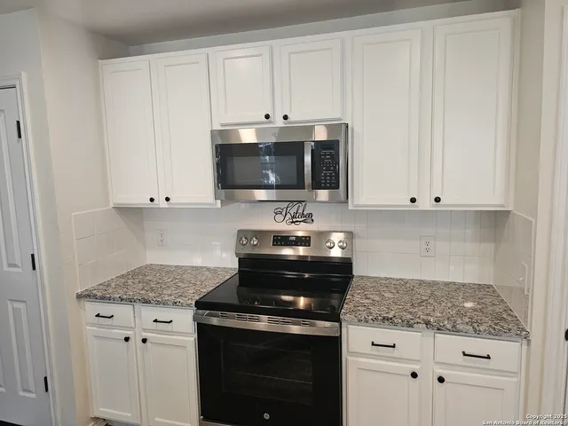a kitchen with granite countertop white cabinets and black appliances