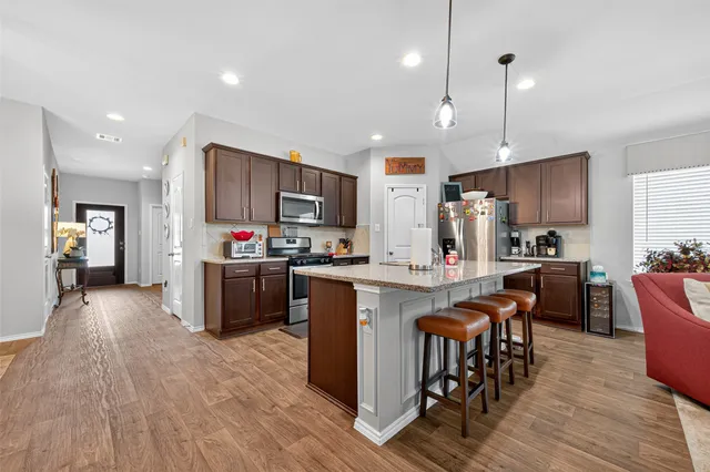 a kitchen with kitchen island granite countertop wooden floors and stainless steel appliances