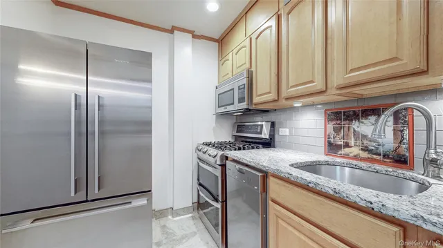 a kitchen with stainless steel appliances granite countertop a sink a refrigerator and a sink