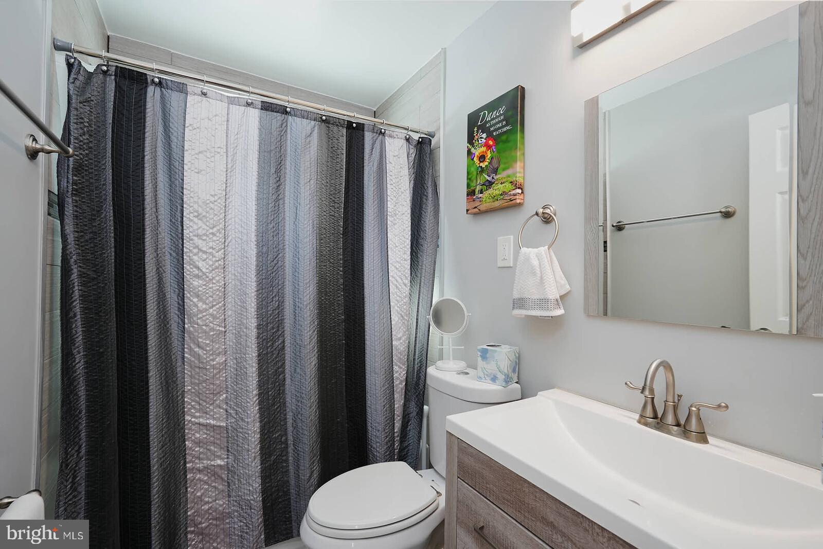 7719 Garrison Road Hyattsville, MD 20784 - Photo 14 of 23 a bathroom with a sink a toilet and shower curtain