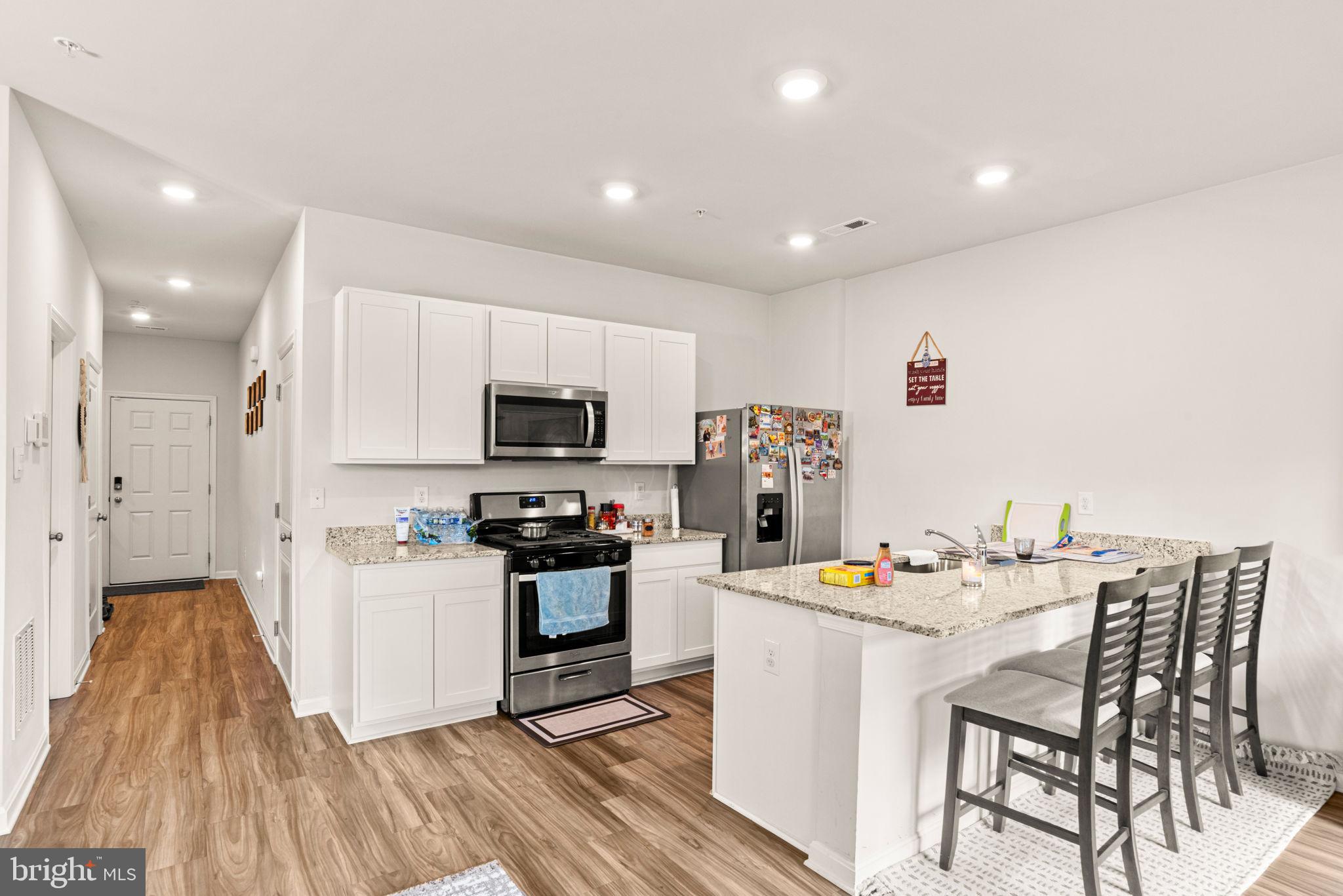 310 Maple Run Drive York, PA 17404 - Photo 5 of 28 a kitchen with stainless steel appliances kitchen island granite countertop a sink dishwasher a stove a refrigerator and a dining table with wooden floor