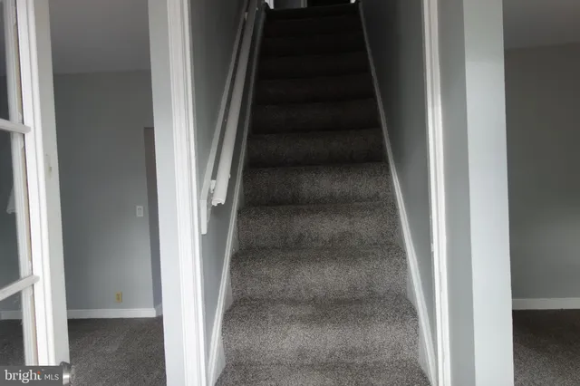 a view of staircase with white walls and white door