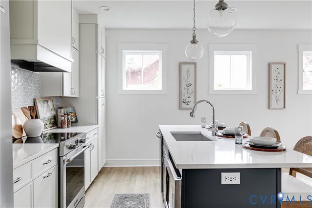 a kitchen with stainless steel appliances a sink dishwasher a stove a dining table and chairs with wooden floor