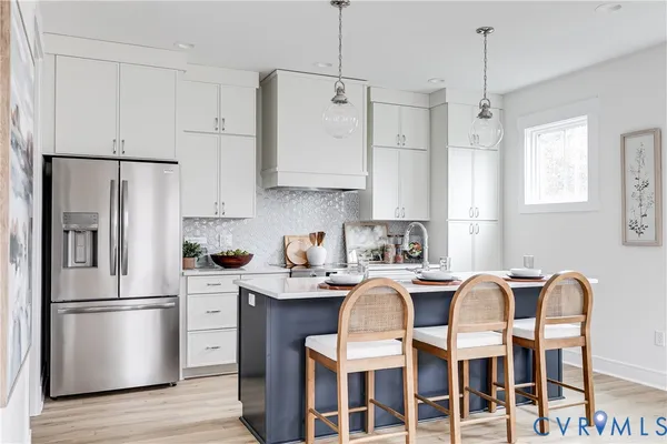 a kitchen with stainless steel appliances granite countertop a refrigerator a stove a sink dishwasher a dining table and chairs with wooden floor