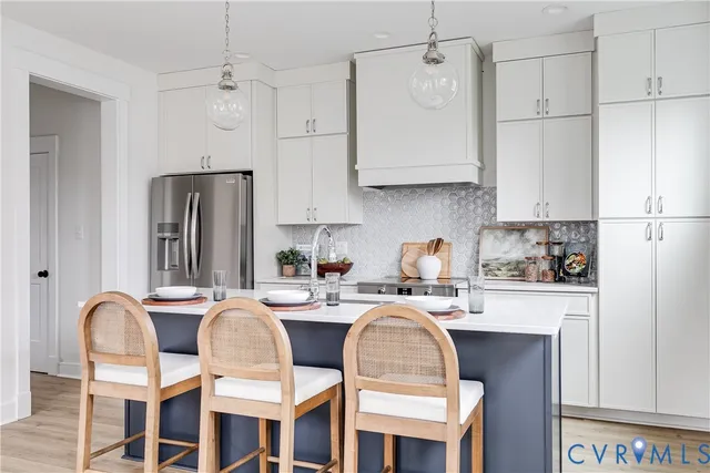 a kitchen with stainless steel appliances granite countertop a dining table chairs refrigerator and sink