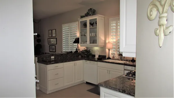 a kitchen with granite countertop white cabinets and white appliances