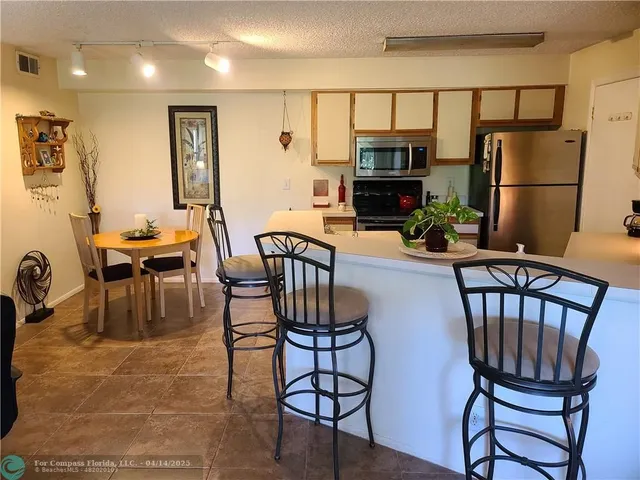 a kitchen with stainless steel appliances a stove a sink a dining table and chairs