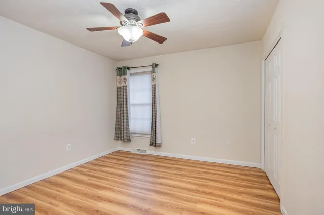 a view of a room with wooden floor and a ceiling fan