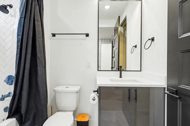 a bathroom with a sink a toilet a mirror and shower