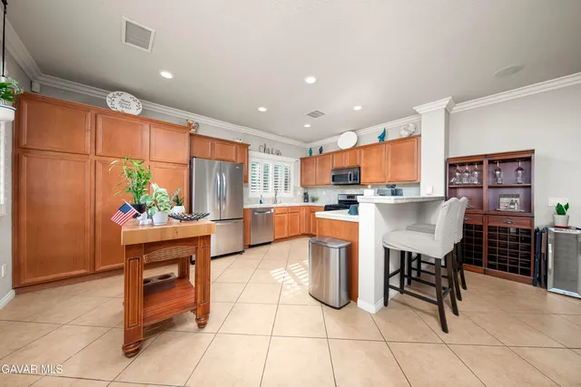 a kitchen with stainless steel appliances kitchen island granite countertop a table chairs and a refrigerator