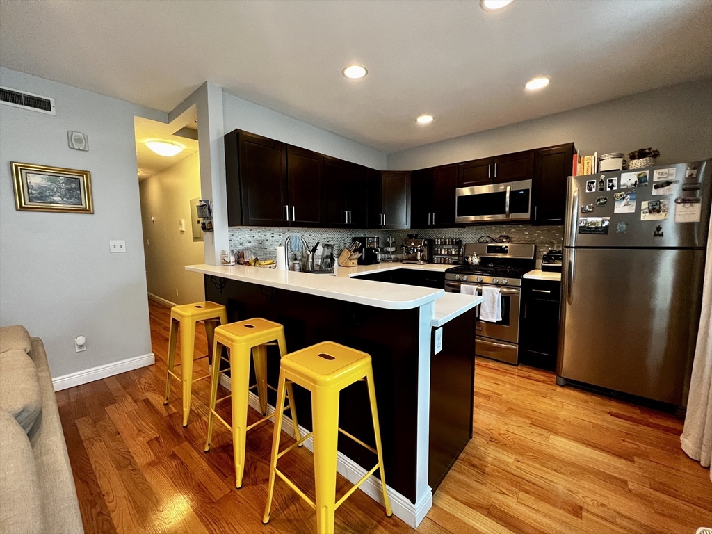 170 I Street, Unit 2 Boston, MA 02127 - Photo 2 of 10 a kitchen with stainless steel appliances granite countertop a sink a stove a refrigerator cabinets and a dining table