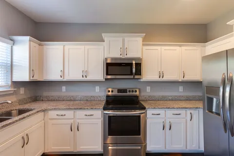 a kitchen with granite countertop white cabinets and stainless steel appliances
