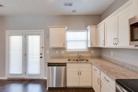 a kitchen with granite countertop white cabinets and white appliances