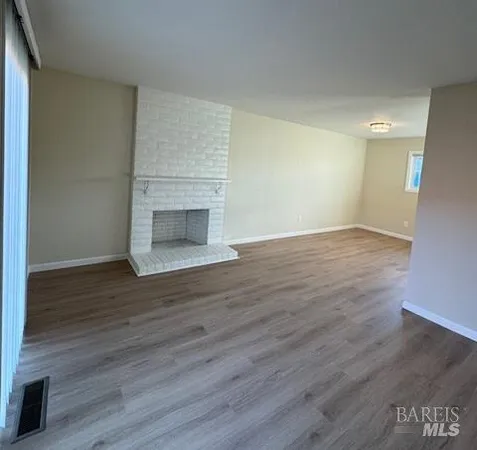 an empty room with wooden floor fireplace and windows
