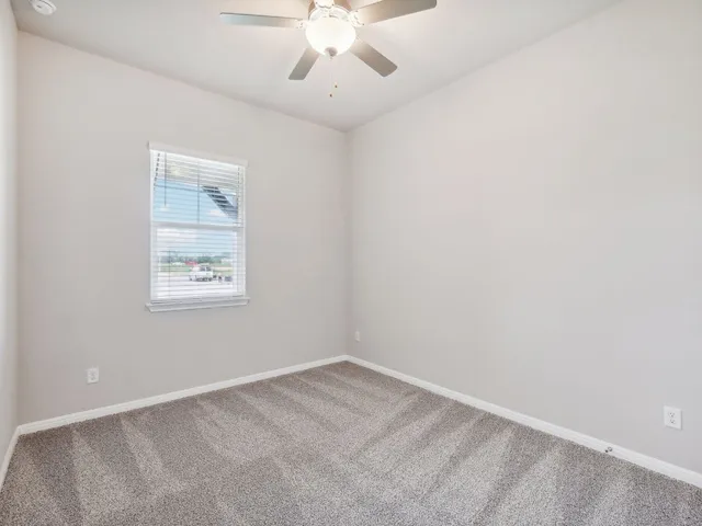 an empty room with a chandelier fan and closet