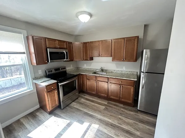 a kitchen with granite countertop a refrigerator a sink a stove a microwave a counter space and cabinets