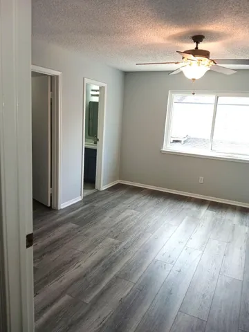 an empty room with wooden floor and windows